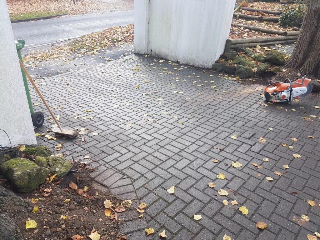 CatFence installer running electronic cat fence cable beneath block-paved driveway