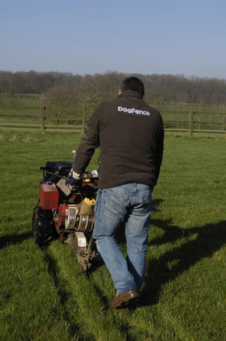 Professional CatFence installer trenching and laying electronic cat fence wire in rural garden